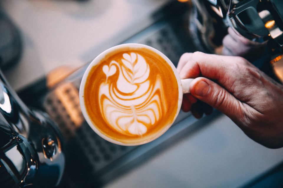Cup of coffee with latte art held in hand